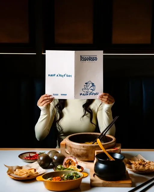 A guest holding the RisoRiso menu at the table